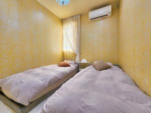 一棟貸しゲストハウス マリドール في إزومو: سريرين توأم في غرفة بها نافذة