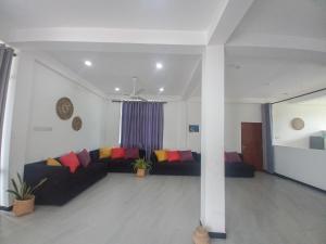 a living room with a couch with colorful pillows at Relax inn modara in Mirissa