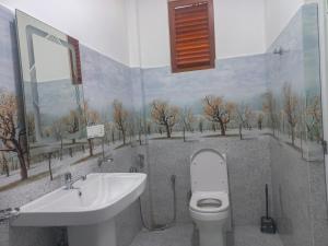 a bathroom with a toilet and a sink with a painting on the wall at Relax inn modara in Mirissa
