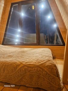 un letto in una camera con una grande finestra di twin cottages a Goderdzi