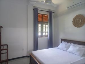 a bedroom with a bed with blue curtains and a window at Relax inn modara in Mirissa +17 photos