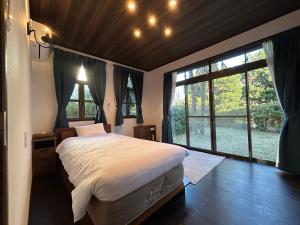 Ogiファミーユ 一碧湖 湖近く 温泉 屋根付バーベキューテラス 1棟貸切宿的一间配有大床和大窗户的卧室 更多25张照片