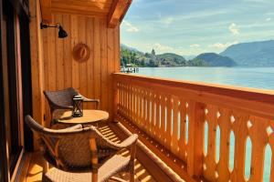 a porch with two chairs and a table and a view of the water at Strandhotel Margaretha in St. Wolfgang