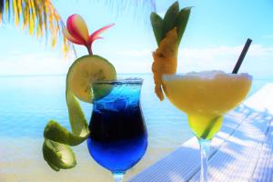 two cocktails sitting on a table next to the ocean at Le Uaina Beach Resort in Falepuna