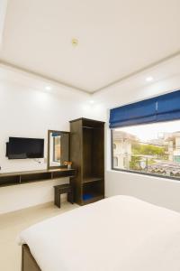 a bedroom with a bed and a tv and a window at Hưng Phú Hotel HCM in Ho Chi Minh City