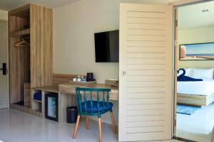 een kamer met een bureau en een blauwe stoel in een hotelkamer bij Aqua Maya Phuket in Patong Beach