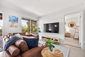Una sala de estar con un sofá y un televisor. en The Surf Nook - Walk to Beach - Family Friendly, en Gracetown