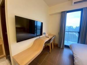 a hotel room with a desk with a large flat screen tv at Yunfeng Hotel 雲峰精品文旅 in Jinning