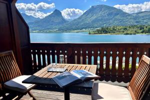 a table and chairs on a balcony with a view of a lake at Strandhotel Margaretha in St. Wolfgang