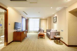 a living room with a couch and a tv at Xiamen Fortune Hotel in Xiamen
