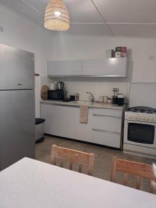 Una cocina con electrodomésticos blancos y una mesa con sillas. en הבית של דובי, en Kfar Blum