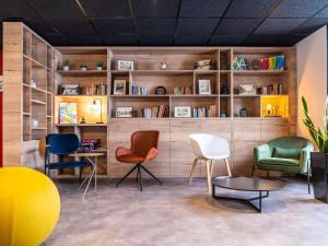a room with chairs and a table and bookshelves at Ibis Pontarlier in Pontarlier