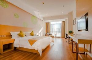 a hotel room with a bed and a desk at GreenTree Inn Qufu High Speed Railway Station in Qufu