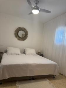 1 dormitorio con 1 cama con ventilador de techo y espejo en הבית של דובי, en Kfar Blum