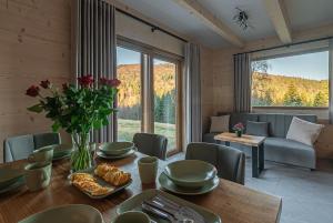 a dining room with a table with flowers and a couch at Zielone Wzgórze Sidzina in Sidzina
