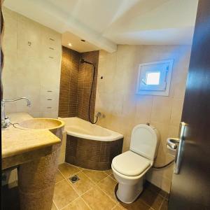 a bathroom with a toilet and a tub and a sink at JD Maisonette for 4 in Neoi Epivates