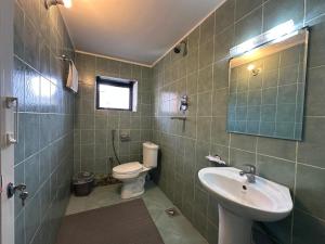 Un baño con lavabo, inodoro y espejo. en Kobaha Stay N Sip, en Pātan 20 fotos más