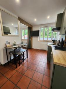 Una cocina con suelo de baldosas y una mesa y encimeras. en Séjour idyllique normand - Appartement cosy à 5 min de la plage - Veules-les-Roses, en Veules-les-Roses 12 fotos más