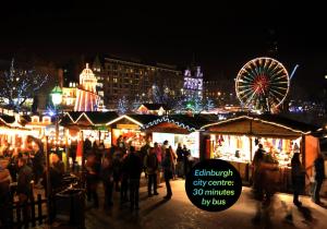 Edinburgh's Winter Chalet في روزلين: زحمة الناس يتجولون في سوق عيد الميلاد بالليل