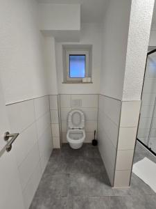 een kleine badkamer met een toilet en een raam bij Nestwerk Solide L16-02 in Biberach an der Riß