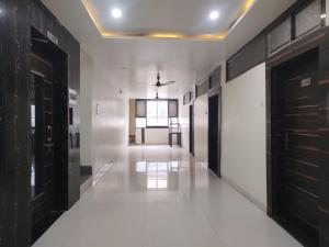 a hallway with white floors and black doors at Hotel Suryadeo in Jabalpur