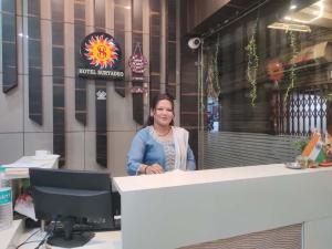 uma mulher em pé atrás de um balcão em frente a um prédio em Hotel Suryadeo em Jabalpur