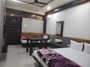 um quarto com duas camas e uma mesa em Hotel Suryadeo em Jabalpur