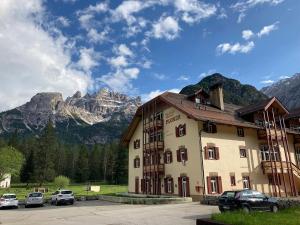 Villaggio Turistico Ploner في كاربونين: مبنى فيه سيارات تقف امام جبل