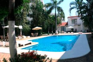 a large blue swimming pool with palm trees and a building at Hotel Olinalá Diamante in Acapulco