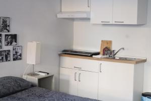 a bedroom with a bed and a sink and white cabinets at porta merlonia house minimono in Forlì
