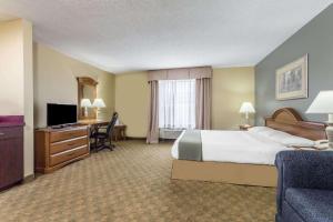 a hotel room with a bed and a desk and a television at Days Inn by Wyndham Selma in Selma