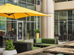 un patio con sombrilla amarilla, mesas y sillas en ibis Dubai Al Rigga, en Dubái