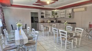 Vicky B Bed and Breakfast في Mogwase: غرفة طعام مع طاولة وكراسي ومطبخ