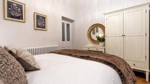 a white bedroom with a bed and a mirror at Plas Madoc Lodge in Conwy