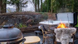 a fire pit with a table and chairs and a grill at Plas Madoc Lodge in Conwy