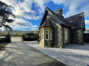 an old stone house on a gravel driveway at Plas Madoc Lodge in Conwy