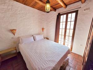 Un dormitorio con una cama y una ventana grande. en jade, en Ubrique