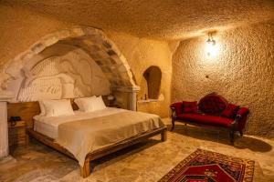 Ages in Cappadocia Premium في أوشيسار: غرفة نوم بها سرير وكرسي أحمر