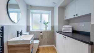 a white bathroom with a sink and a mirror at Plas Madoc Coach House in Conwy +97 photos