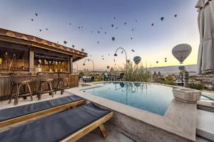 a hotel with a pool and a bar and hot air balloons at Cappadocia Inn Cave Hotel in Goreme