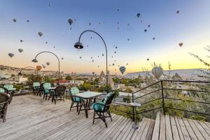 a deck with tables and chairs and hot air balloons at Cappadocia Inn Cave Hotel in Göreme +183 photos