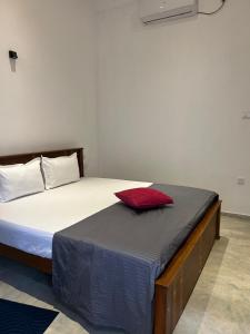 a bed in a room with a red pillow on it at Costal View-Ahangama in Ahangama