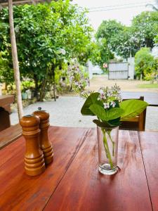 a glass vase with flowers on a wooden table at Costal View-Ahangama in Ahangama