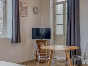 a dining room with a table and a tv at La Rose Urban avec Parking privé et Gare à 2 min in Nogent-le-Rotrou