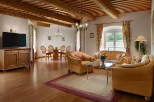 a living room with couches and a tv and a table at Klosterhof St. Salvator in Bad Griesbach