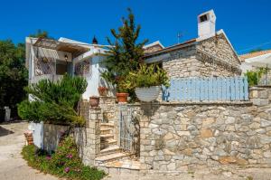a stone house with a fence and potted plants at Thodoroulis in Boïkátika