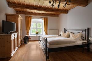 a bedroom with a bed and a tv and a window at Klosterhof St. Salvator in Bad Griesbach
