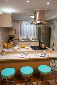 a kitchen with a counter with four bar stools at B&B Apartamento Completo e Decorado com 3 Quartos in São José dos Pinhais