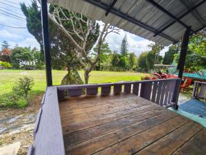 a wooden bench on a porch with a view of a park at เขาค้อ ภูดาว Resort & Camping in Khao Kho