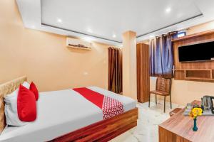Un dormitorio con una cama con almohadas rojas y un televisor en Hotel O Karaikal Beachview Formerly KK Residency, en Karaikal